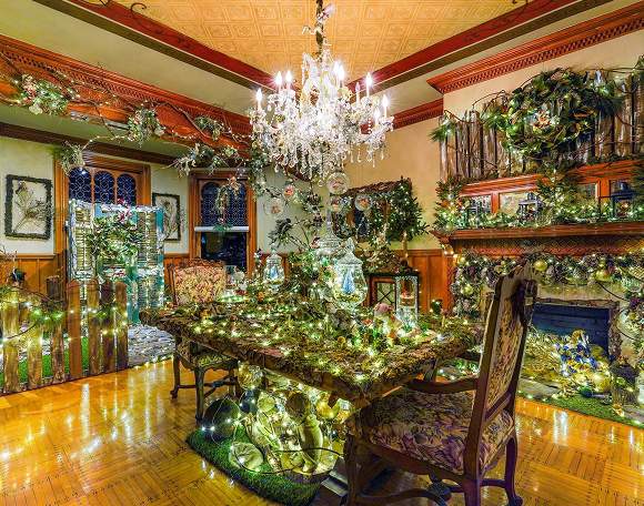 A dining room dressed for Christmas beneath a lit chandelier