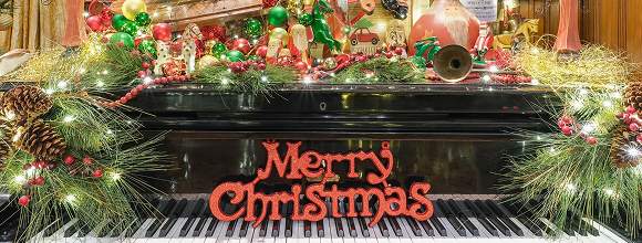 A grand piano garlanded with Merry Christmas lettering